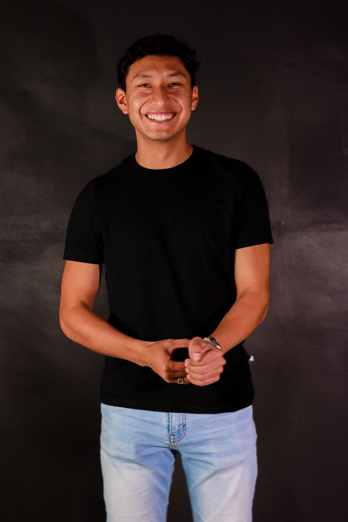 Man wearing slim-fit black crew neck tee with light jeans — studio lifestyle shot